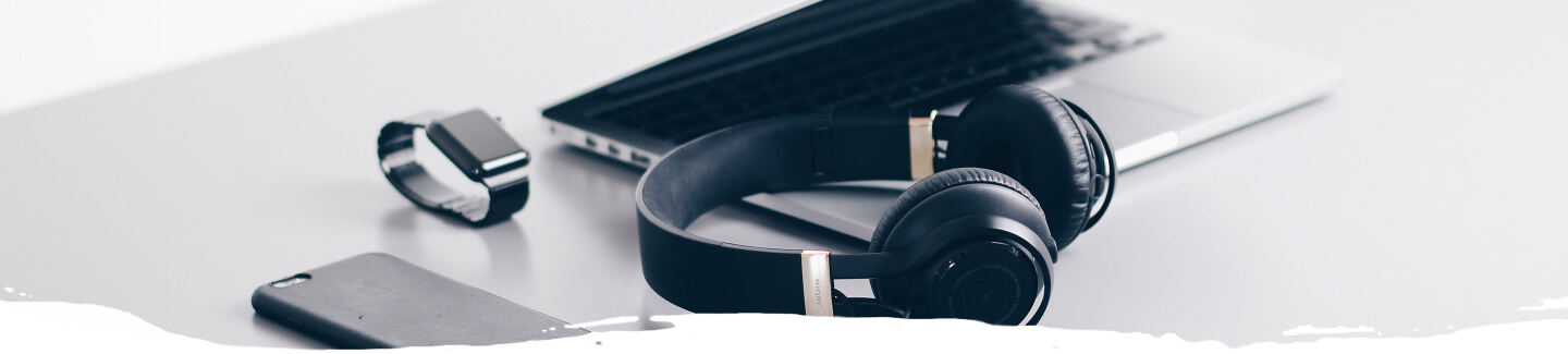 Table with smartphone, laptop, headphones and smartwatch on top